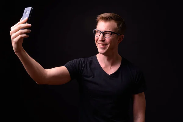 Porträt eines glücklichen jungen gutaussehenden Mannes mit Brille, der ein Selfie macht — Stockfoto