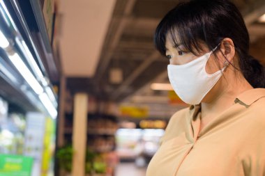 Corona virüsü salgınından korunmak için maske takan şişman Asyalı kadının portresi süpermarkette