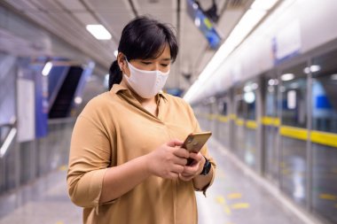 Metro istasyonundaki Corona virüsü salgınından korunmak için maskeli şişman Asyalı kadının portresi