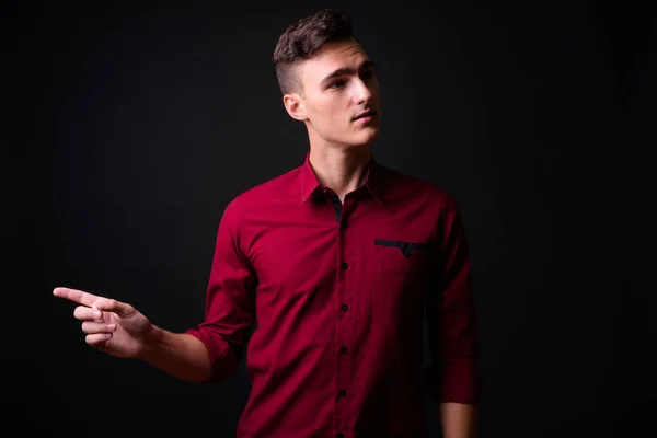 黒を背景にした赤いシャツを着た若いハンサムなビジネスマンのスタジオショット — ストック写真