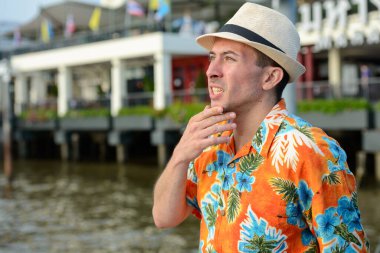 Bangkok 'taki nehir manzarasına karşı rıhtımdaki yakışıklı turistin portresi.
