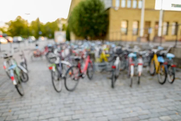 Fila desenfocada de bicicletas aparcamiento en squarestreet cerca de patio cercado y edificio — Foto de Stock