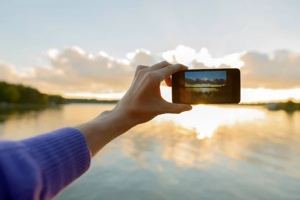 Hände eines jungen Mannes, der Fotos mit dem Handy des schönen Sonnenuntergangs macht — Stockfoto