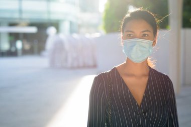 Sokaklarda Corona virüsü salgınından korunmak için maske takan Asyalı genç iş kadını portresi