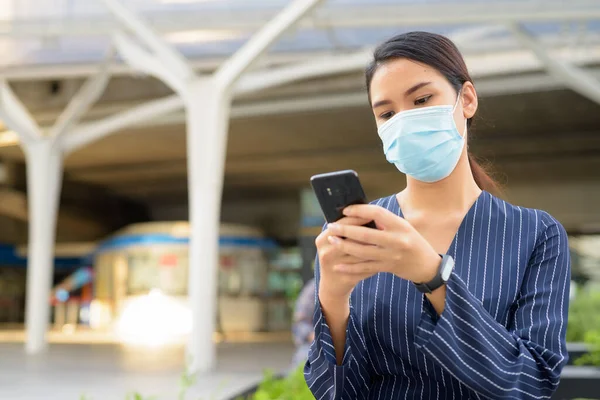 Şehirdeki Corona virüsü salgınından korunmak için maske takan Asyalı genç iş kadını portresi.
