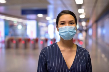Metro istasyonunda Corona virüsü salgınından korunmak için maske takan Asyalı genç iş kadınının portresi.