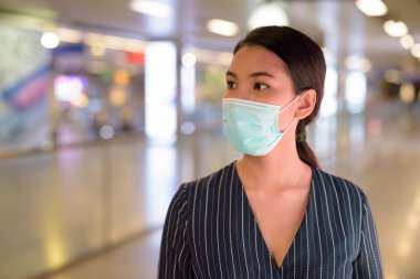 Metro istasyonunda Corona virüsü salgınından korunmak için maske takan Asyalı genç iş kadınının portresi.