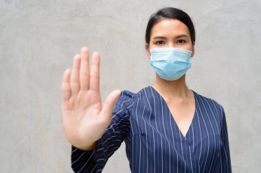 Korona virüsü salgınından korunmak için maske takan Asyalı genç bir iş kadınının portresi.