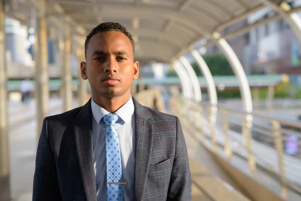 市内のスカイウォーク橋でスーツを着た若いハンサムなアフリカ人ビジネスマンの肖像画 — ストック写真