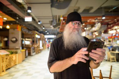 Alışveriş merkezinde gözlüklü yetişkin sakallı hippi turist portresi.
