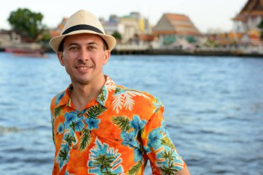 Bangkok 'taki nehir manzarasına karşı rıhtımdaki yakışıklı turistin portresi.