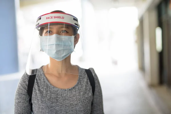 Portrait of young Filipino woman with mask for protection from corona virus outbreak in the city streets outdoors