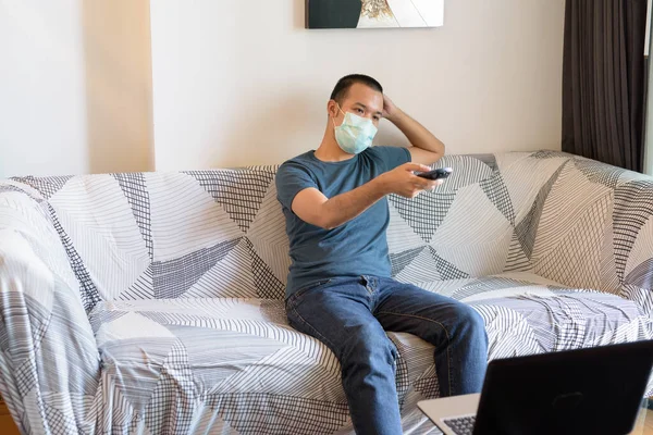 Portrait of young Asian man with mask for protection from corona virus outbreak staying at home under quarantine