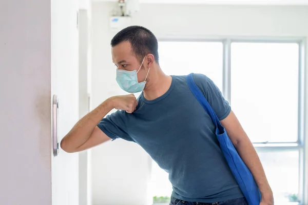 Portrait of young Asian man with mask for protection from corona virus outbreak practicing proper hygiene etiquette