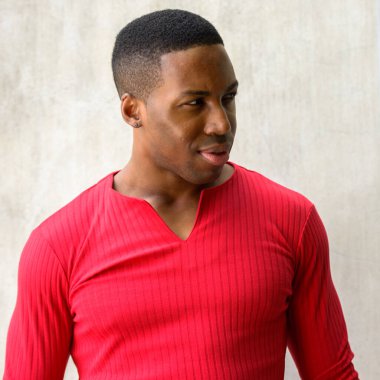 Portrait of young handsome muscular African man against concrete wall outdoors