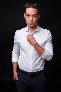 Studio shot of young handsome multi ethnic businessman against black background