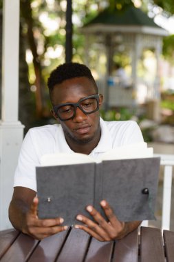 Portrait of young African nerd man as student with eyeglasses at the park outdoors
