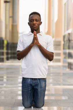 Portrait of young African man at modern building in the city outdoors