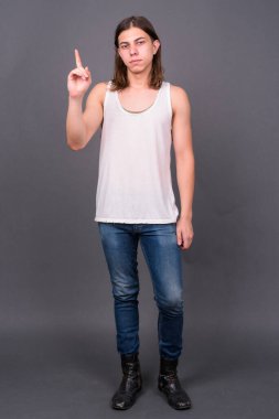 Studio shot of young handsome androgynous man with long hair against gray background