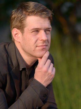 Portrait of young handsome businessman relaxing in nature outdoors