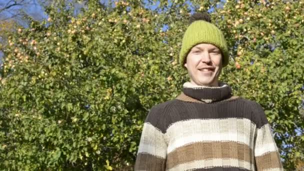 Gesicht eines glücklichen jungen Mannes, der im Herbst einen Apfel im Park hält — Stockvideo