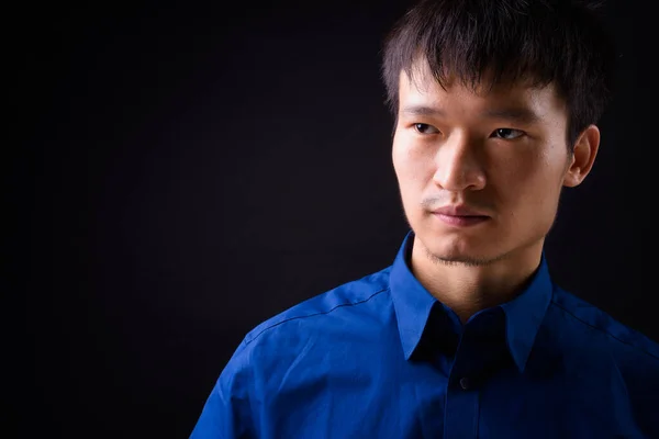 黒を背景に青いシャツを着た若い中国人ビジネスマンのスタジオショット — ストック写真