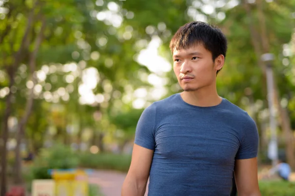 Portrét mladého Asiata v parku venku — Stock fotografie