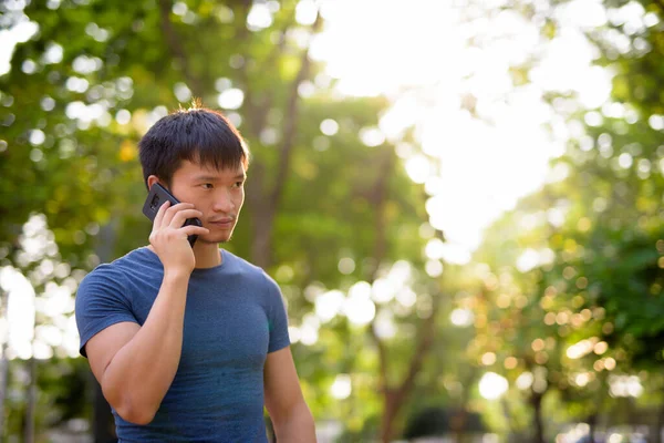 Portrait de jeune homme asiatique parlant au téléphone au parc en plein air — Photo