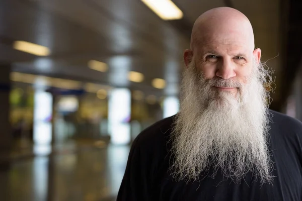 Face of mature handsome bald bearded man at the subway train station