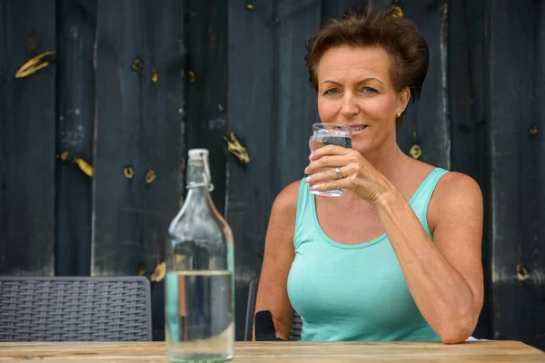 행복하고 아름다운 여인 이 야외 식당에서 물을 마시고 있다 — 스톡 사진