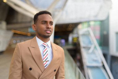 Şehirdeki yaya köprüsünü düşünen genç ve yakışıklı bir Afrikalı işadamı.