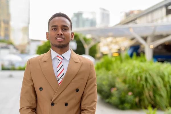 Feliz joven guapo empresario africano sonriendo en la ciudad al aire libre —  Fotos de Stock