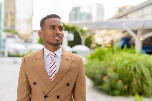 Glad ung vacker afrikansk affärsman tänker i staden utomhus — Stockfoto