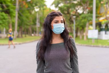 Portrait of young Indian woman with mask for protection from corona virus outbreak in the streets at the park outdoors