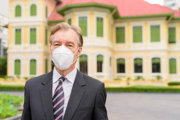 Visage d'homme d'affaires mature avec masque pour la protection contre l'épidémie de virus de la couronne dans la ville en plein air — Photo