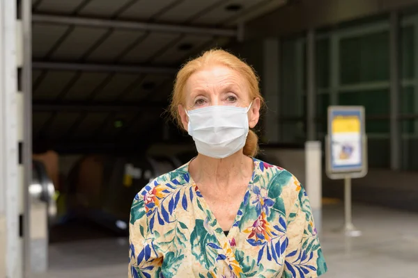 Szőke idős nő maszkot visel, hogy megvédje a koronavírus kitörésétől a metró vasútállomáson a szabadban — Stock Fotó