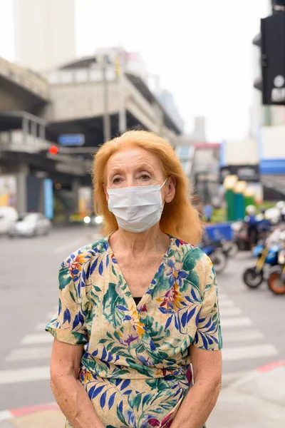 Portré szőke idős nő maszk gondolkodás a városban a szabadban — Stock Fotó