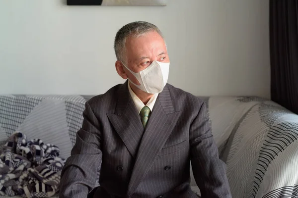 Mature Japanese businessman with mask staying at home under quarantine — Stock Photo, Image