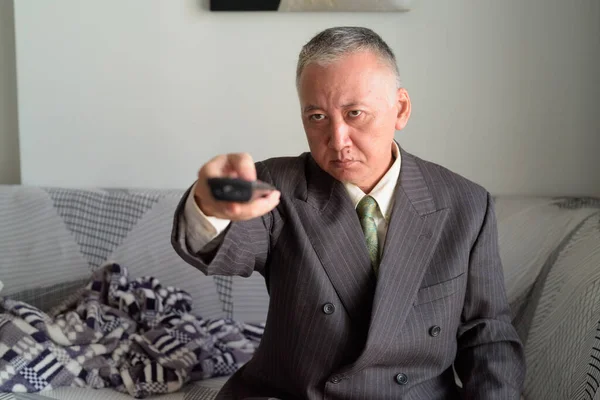 Mature Japanese businessman watching tv in the living room at home — Stock Photo, Image