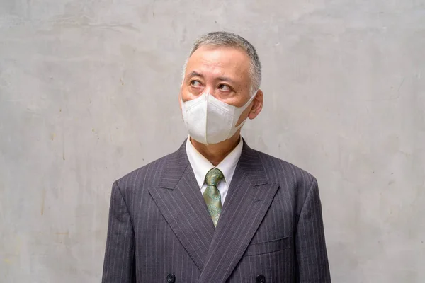 Visage d'homme d'affaires japonais mature avec masque pensant à l'extérieur — Photo