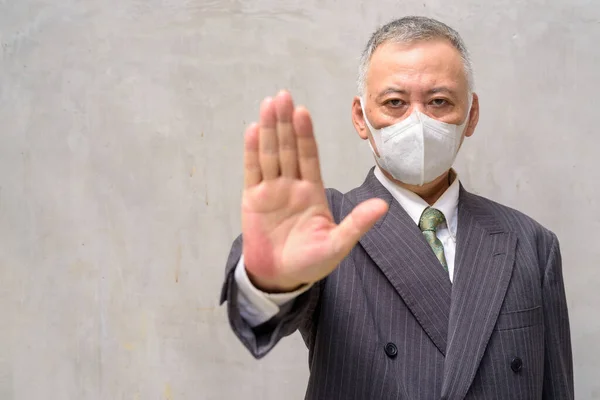 Stressé mature japonais homme d'affaires avec masque montrant stop geste à l'extérieur — Photo