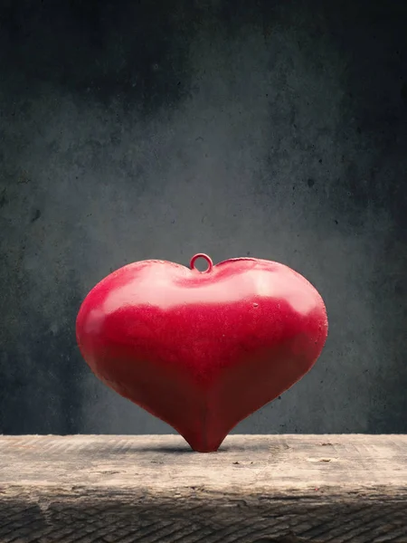 Corazón de metal rojo sobre una mesa de madera — Foto de Stock