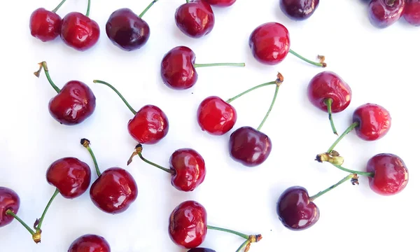 Cerezas rojas esparcidas sobre blanco — Foto de Stock