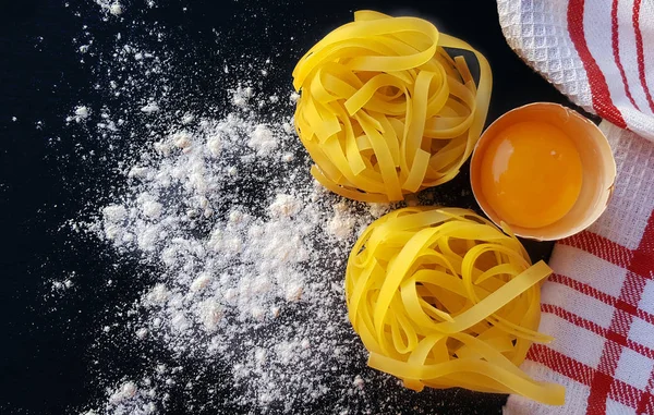 Pâtes tagliatelles maison aux œufs sur carton foncé — Photo