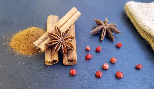 Steranijs, kaneel stokjes en poeder met rode peper op tafel — Stockfoto