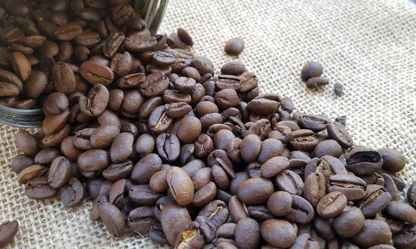 Granos de café en una bolsa sobre fondo de lona — Foto de Stock
