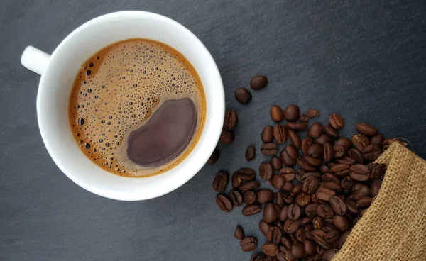 暗い背景上に豆とコーヒー カップ — ストック写真
