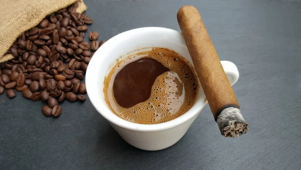 Taza de café, frijoles y cigarros sobre fondo oscuro — Foto de Stock