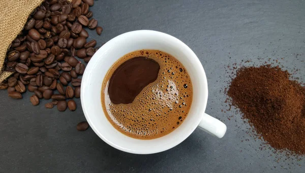 Coffee cup, beans and ground powder on dark  background — Stock Photo, Image