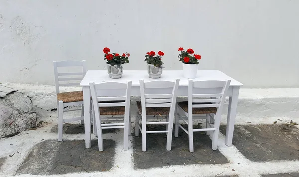 Bílý stůl s krásnou floewers a židle v pouliční restauraci na ostrově Mykonos — Stock fotografie